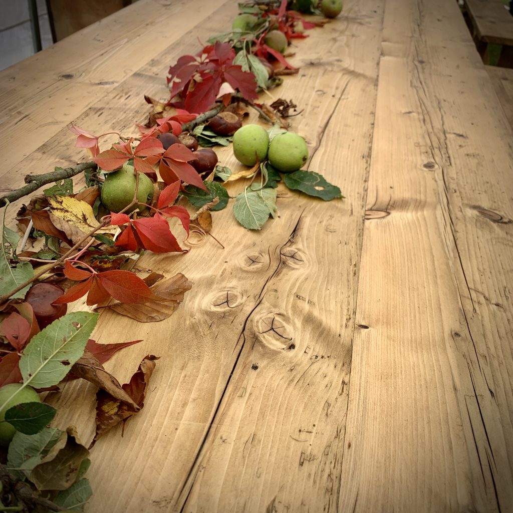 Wooden trestle table for hire decorated in autumnal leaves